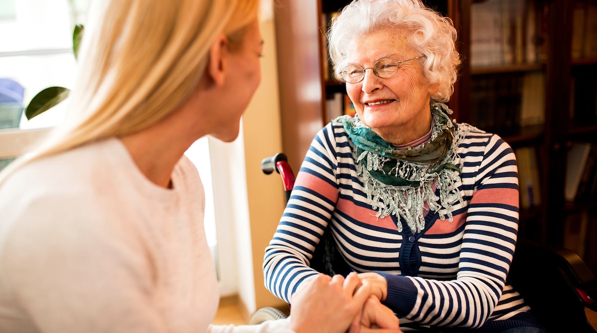 smiling senior woman holding a caregiver's hand