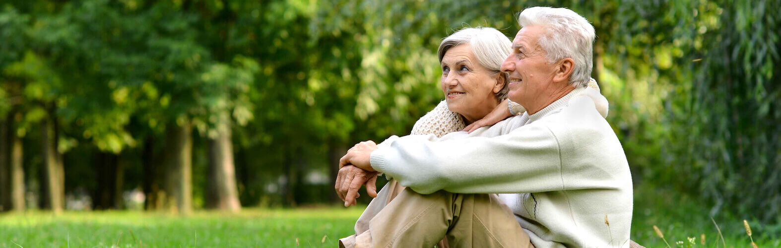 Couple Sitting On Green Grass In The Summer Park