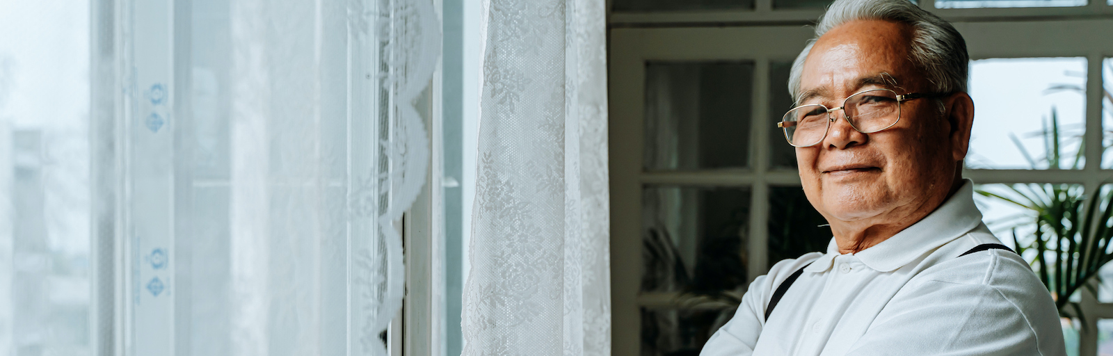 Confident ethnic man standing near window at home