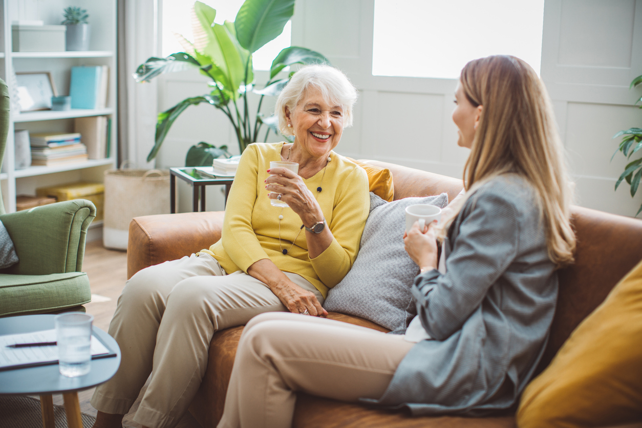 Senior woman talking with female financial or real estate advisor at home.