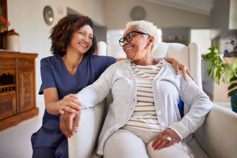 senior woman sitting on chair with nurse behind her