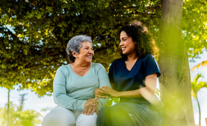 Home caregiver and senior woman talking outdoors