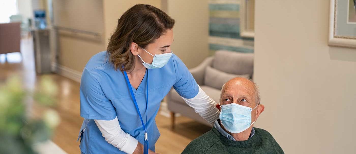 senior and healthcare worker with face masks on walking through a senior living community